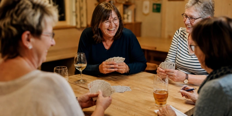 Nahaufnahme einer Hand, die Skatkarten hält, deutsche Spielkarten mit Eicheln und Schellen